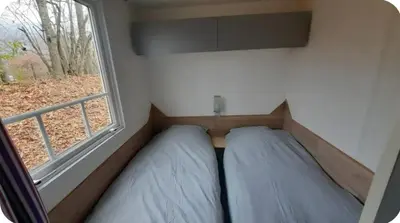 two beds in a small room with a window at MH F4 Ski Rando Loisirs Proche Chamonix 6 pers 300AK in Passy