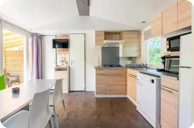 a kitchen with wooden cabinets and a table with chairs at MH F4 Ski Rando Loisirs Proche Chamonix 6 pers 300AK in Passy