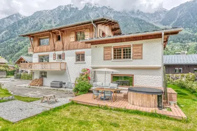 a house with a wooden deck and a table at Appartement de Luxe avec Jacuzzi, Vue Montagne et Jardin in Chamonix-Mont-Blanc
