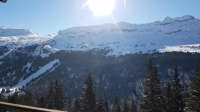 a snow covered mountain with trees and the sun at Résidence Les Terrasses D'eos - Appartement spacieux · Accès direct aux pistes · Piscine · WIFI gratuit et illimité · Spa MAE-1661 in Magland
