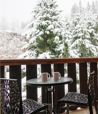 a table and chairs on a balcony with a snow covered tree at Au centre du village station de ski in Les Contamines-Montjoie