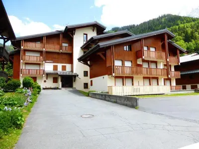 a large building with a parking lot in front of it at Au centre du village station de ski in Les Contamines-Montjoie