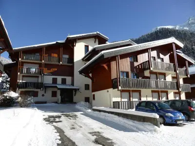 a large building with cars parked in a parking lot at Au centre du village station de ski in Les Contamines-Montjoie
