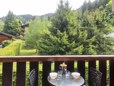 a table on a balcony with a view of trees at Au centre du village station de ski in Les Contamines-Montjoie
