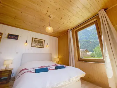 a bedroom with a bed with a large window at Le cosy refuge in Chamonix-Mont-Blanc