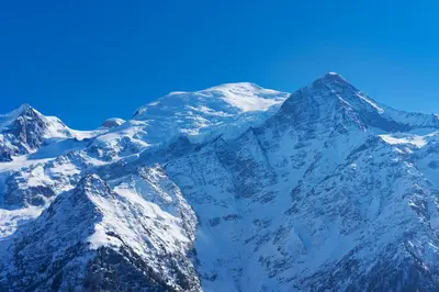 a snow covered mountain with a blue sky at Le cosy refuge in Chamonix-Mont-Blanc