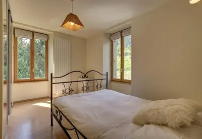 a bedroom with a bed with white sheets and windows at Apartment Serenite in Chamonix-Mont-Blanc