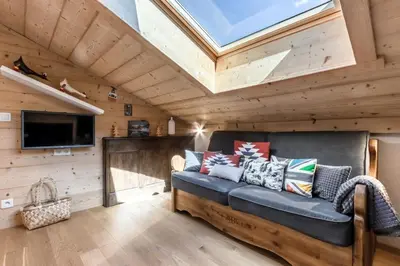 a living room with a blue couch and a skylight at Balcon du Mont-Blanc - Calme - Central in Chamonix-Mont-Blanc
