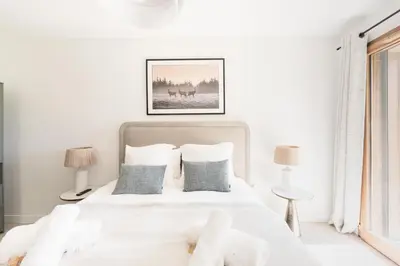 a white bedroom with a white bed with pillows at SUNNY MEGEVE - Luxury Flat with services in Megève