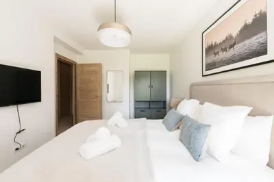 a bedroom with a white bed with a flat screen tv at SUNNY MEGEVE - Luxury Flat with services in Megève