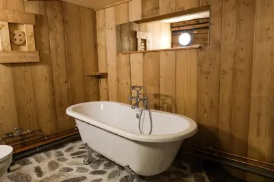 a bath tub in a bathroom with wooden walls at Refuge Margot in Chamonix-Mont-Blanc