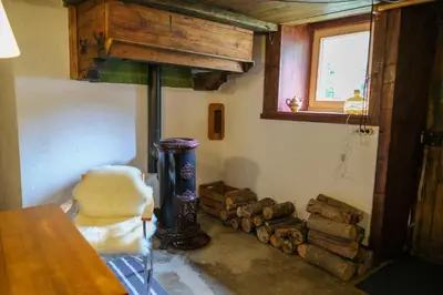 a room with a wood stove and a pile of logs at Refuge Margot in Chamonix-Mont-Blanc