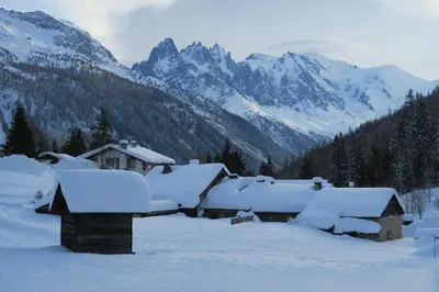 a house covered in snow with mountains in the background at Refuge Margot in Chamonix-Mont-Blanc