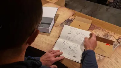 a man sitting at a table writing on paper with a printer at Bivouac & Sacs à dos - Loft classé, avec escape game sur demande in Sixt