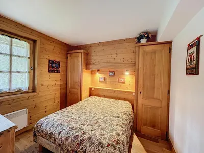 a bedroom with a bed in a room with wooden walls at Appartement 3P avec parking proche des pistes à Combloux - FR-1-560-135 in Combloux