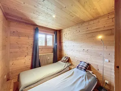two beds in a wooden room with a window at Appartement 4 pièces avec piscine couverte à Combloux - FR-1-560-127 in Combloux
