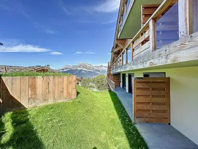 a house with a grassy yard next to a building at Appartement d'Exception 2 Chambres, 63 m², au Pied des Pistes, Parking Inclus, Wi-Fi - FR-1-560-142 in Combloux