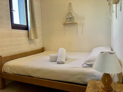 a bed with white sheets and pillows next to a window at Mont Lachat - Central - Vues magnifiques in Saint-Gervais-les-Bains
