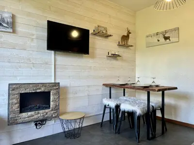 a room with a fireplace and a table and stools at Mont Lachat - Central - Vues magnifiques in Saint-Gervais-les-Bains