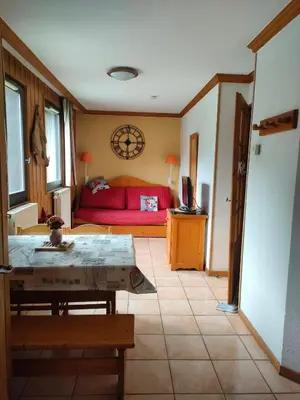 a living room with a red bed and a table at charmant appartement 2-4 personnes coeur de chamonix in Chamonix-Mont-Blanc