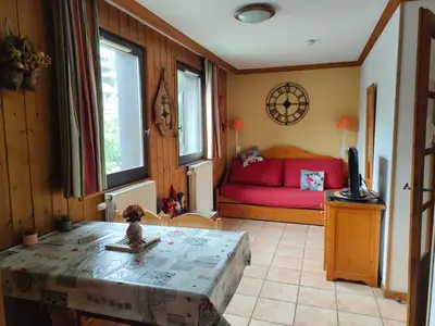 a living room with a red couch and a table at charmant appartement 2-4 personnes coeur de chamonix in Chamonix-Mont-Blanc