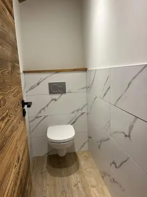 a bathroom with a white toilet and marble walls at Appartement cosy rénové in Megève