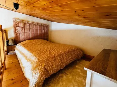 a bed in a bedroom with a wooden ceiling at Appartement Calme et Chaleureux in Demi-Quartier