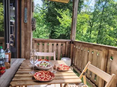 a wooden table with food and wine glasses on a porch at Appartement Calme et Chaleureux in Demi-Quartier