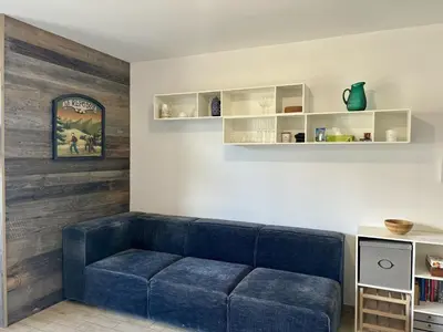 a living room with a blue couch and shelves at Le Bettex - Lumineux - Vue montagne in Saint-Gervais-les-Bains