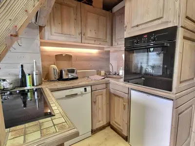 a kitchen with wooden cabinets and a black appliance at Appartement de standing Mont d'Arbois in Megève