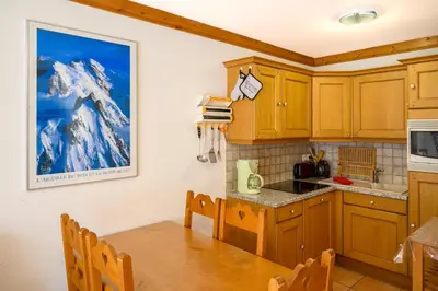 a kitchen with wooden cabinets and a dining room table at Le Névé in Saint-Gervais-les-Bains