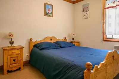 a bedroom with a bed with blue sheets and a window at Le Névé in Saint-Gervais-les-Bains