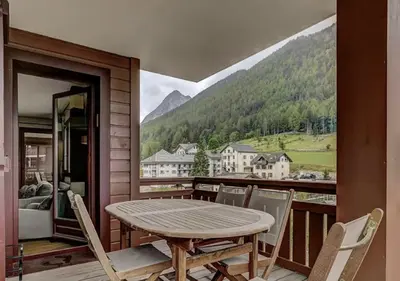 a table and chairs on a balcony with a view of a mountain at Charming Apartment Chamonix Valley in Vallorcine