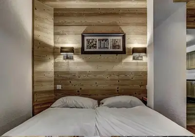 a bedroom with a wooden accent wall with a bed at Charming Apartment Chamonix Valley in Vallorcine