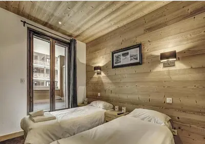 two beds in a room with a wooden wall at Charming Apartment Chamonix Valley in Vallorcine