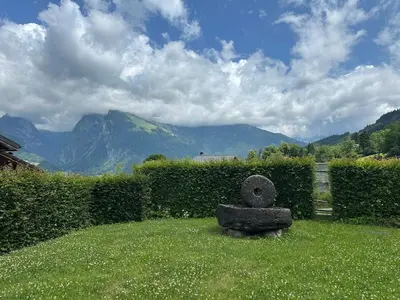 a stone statue in the grass with mountains in the background at Appartement 6p à Samoëns avec parking, proche télécabine - FR-1-642-90 in Samoëns