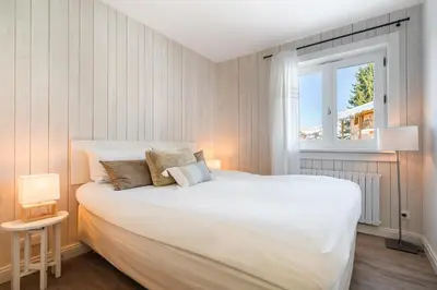 a bedroom with a large white bed and a window at Flat La Loge - At the foot of the Jaillet in Megève in Megève