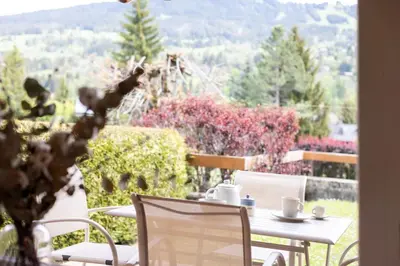 a table and chairs on a balcony with a view of a garden at Flat La Loge - At the foot of the Jaillet in Megève in Megève