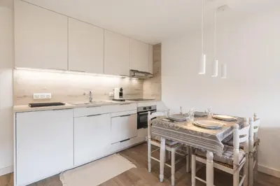 a kitchen with white cabinets and a table with chairs at Flat La Loge - At the foot of the Jaillet in Megève in Megève