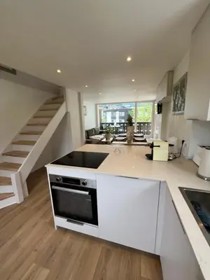 a kitchen with white cabinets and a sink and a staircase at Residence VARLOPE in Chamonix-Mont-Blanc