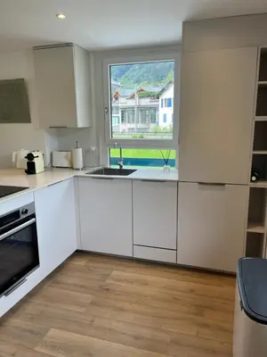 a kitchen with white cabinets and a window at Residence VARLOPE in Chamonix-Mont-Blanc