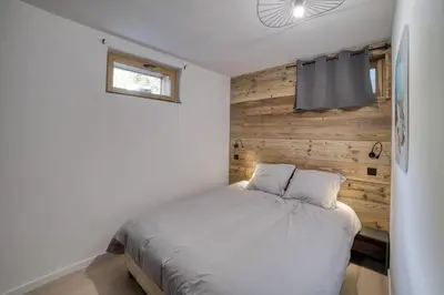 a bedroom with a white bed with a wooden wall at Chalet mitoyen - Jacuzzi - Cousinade I in Les Contamines-Montjoie