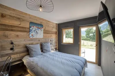 a bedroom with a bed with a wooden wall at Chalet mitoyen - Jacuzzi - Cousinade I in Les Contamines-Montjoie