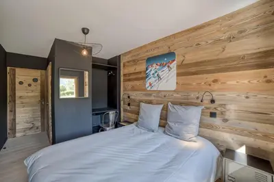 a bedroom with a white bed with a wooden wall at Chalet mitoyen - Jacuzzi - Cousinade I in Les Contamines-Montjoie
