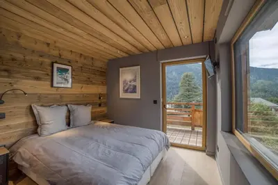 a bedroom with a large bed and a large window at Magnifique chalet mitoyen - Jacuzzi - Cousinade II in Les Contamines-Montjoie