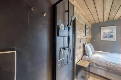 a small room with a bed and a shower at Magnifique chalet mitoyen - Jacuzzi - Cousinade II in Les Contamines-Montjoie