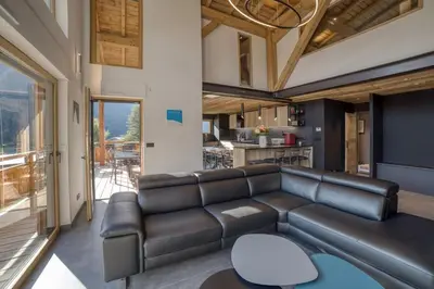 a living room with a leather couch and a kitchen at Magnifique chalet mitoyen - Jacuzzi - Cousinade II in Les Contamines-Montjoie