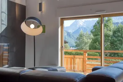 a living room with a couch and a large window at Magnifique chalet mitoyen - Jacuzzi - Cousinade II in Les Contamines-Montjoie