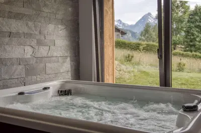 a bath tub filled with water next to a window at Magnifique chalet mitoyen - Jacuzzi - Cousinade II in Les Contamines-Montjoie