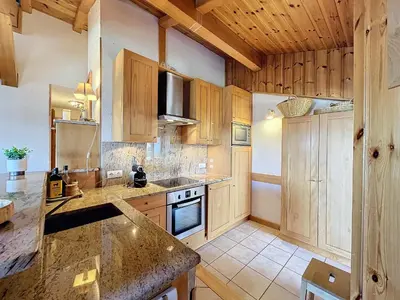 a kitchen with wooden cabinets and a counter top at Appartement 3 pièces tout équipé avec balcon et box fermé, à 1,2 km du centre de Combloux - FR-1-560-141 in Combloux